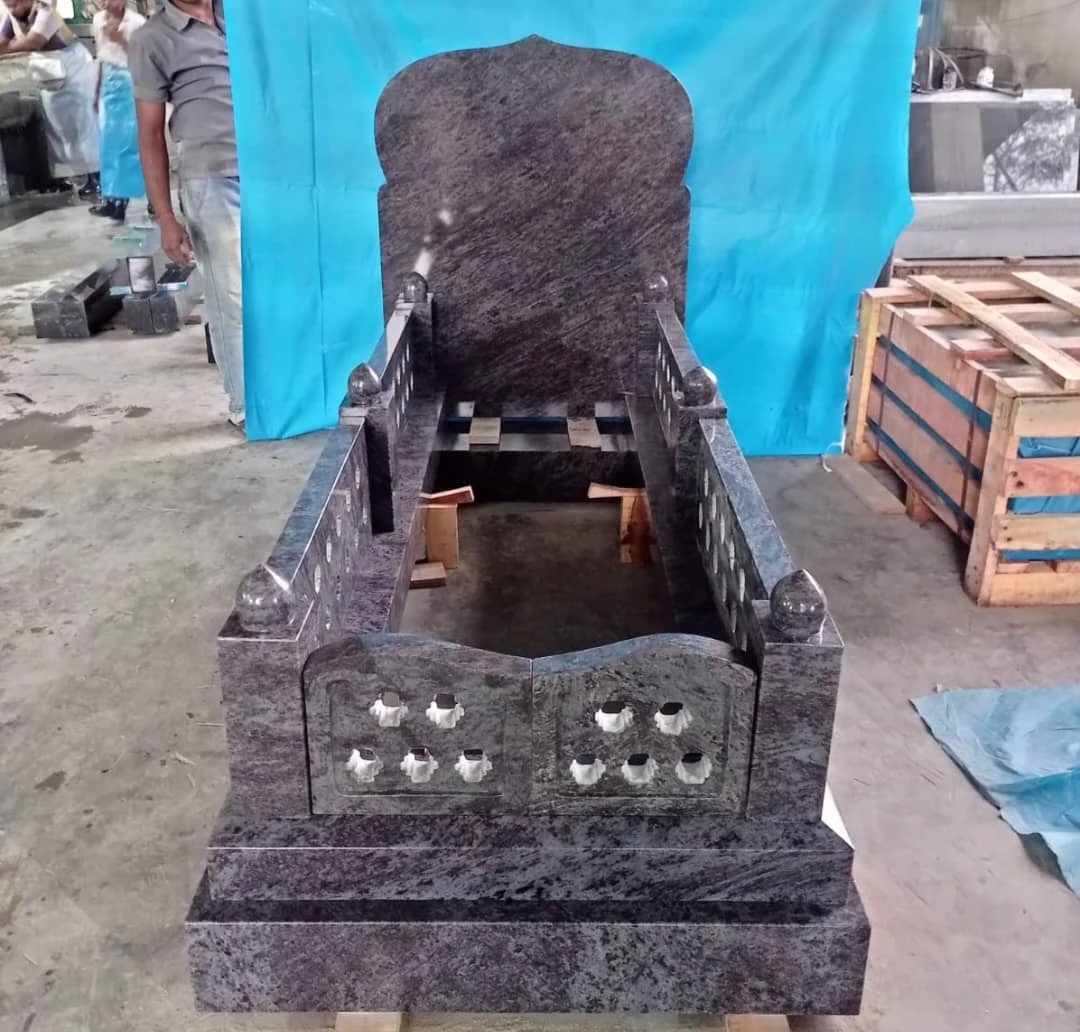 Purple-grey memorial with a rounded headstone and a decorative pierced foot panel, shown in the workshop.